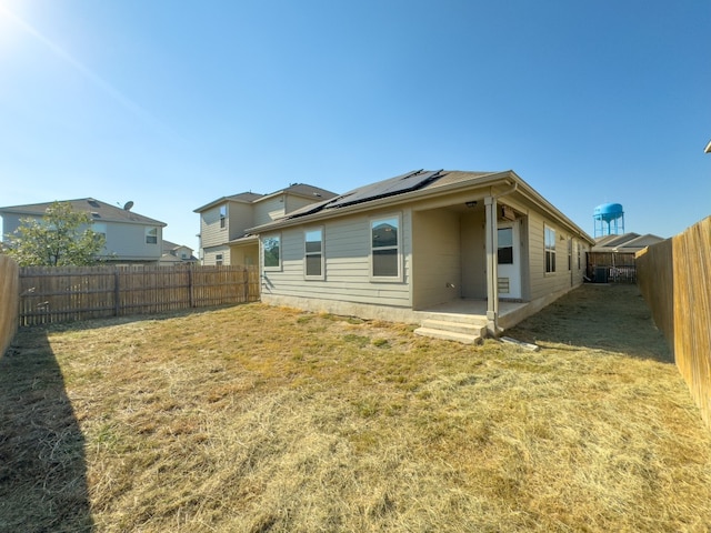 back of house with a yard, a patio area, and solar panels