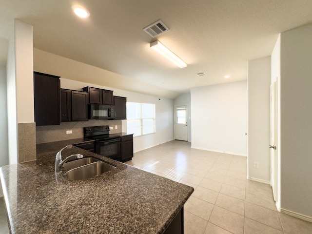 kitchen with tasteful backsplash, black appliances, sink, vaulted ceiling, and light tile patterned floors