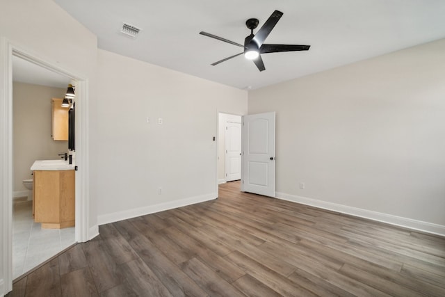 unfurnished bedroom with ensuite bath, sink, wood-type flooring, and ceiling fan