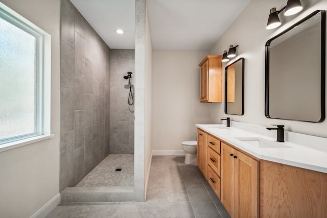 bathroom featuring vanity, tiled shower, toilet, and tile patterned flooring