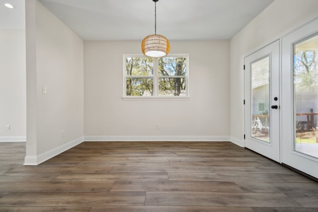 unfurnished dining area featuring dark wood-type flooring, french doors, and a wealth of natural light