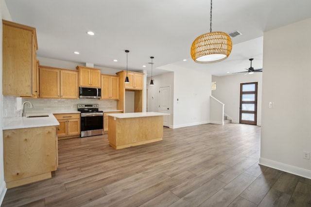 kitchen featuring stainless steel appliances, wood-type flooring, sink, a center island, and pendant lighting