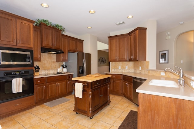 kitchen with a kitchen island, backsplash, light tile patterned floors, black appliances, and sink