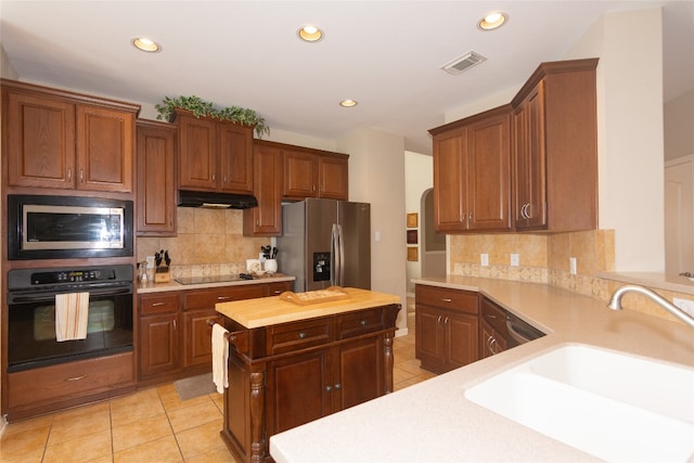 kitchen with black appliances, sink, wood counters, decorative backsplash, and light tile patterned floors