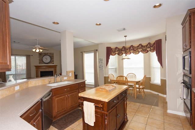 506 Fern Ct, Cedar Park, TX 78613 - kitchen with stainless steel appliances, a tile fireplace, light tile patterned flooring, ceiling fan, and butcher block countertops