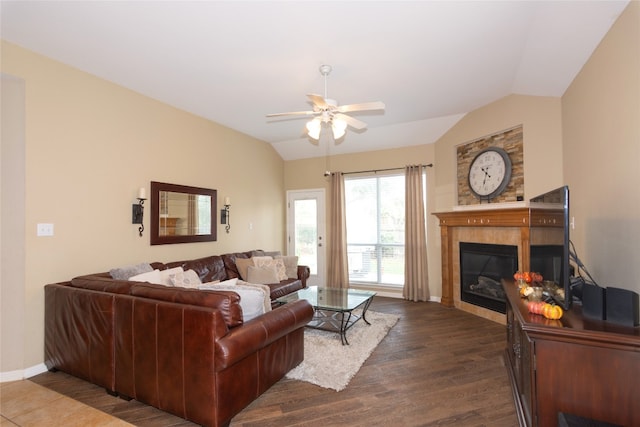 living room featuring vaulted ceiling, a tiled fireplace, dark hardwood / wood-style floors, and ceiling fan