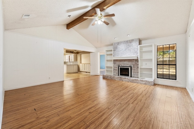 unfurnished living room featuring vaulted ceiling with beams, a textured ceiling, a brick fireplace, ceiling fan, and light hardwood / wood-style flooring