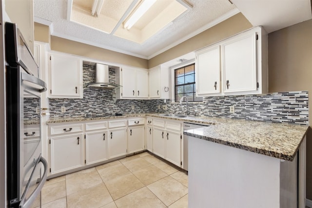 kitchen with light stone countertops, sink, backsplash, wall chimney exhaust hood, and white cabinets