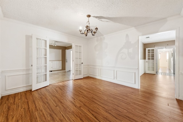 empty room featuring french doors, wood-type flooring, and a textured ceiling