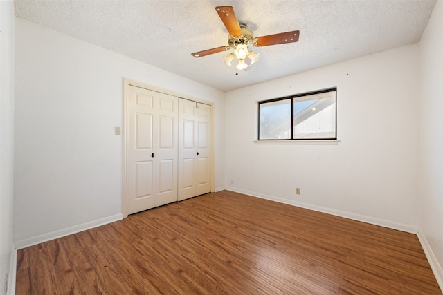 unfurnished bedroom featuring a closet, a textured ceiling, hardwood / wood-style flooring, and ceiling fan