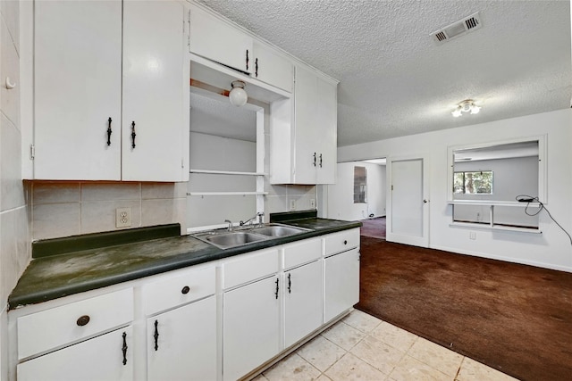 kitchen with white cabinetry, sink, light colored carpet, and a textured ceiling