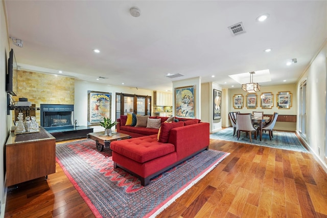 living room with a notable chandelier, hardwood / wood-style floors, a fireplace, and crown molding