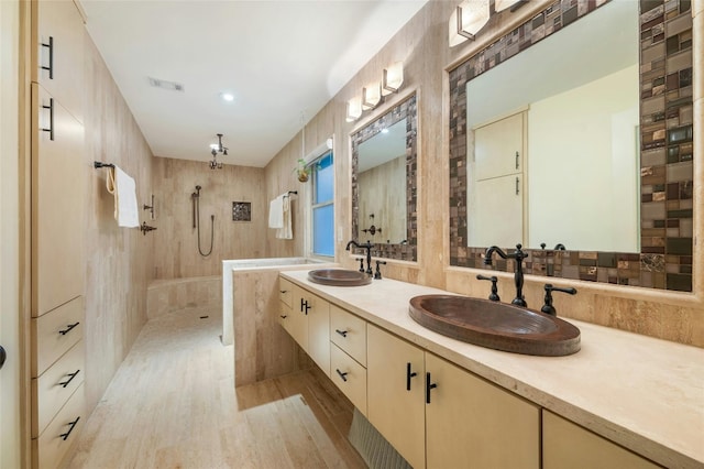 bathroom with vanity, hardwood / wood-style flooring, a shower, and tile walls