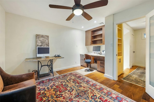 home office with hardwood / wood-style floors, built in desk, and ceiling fan