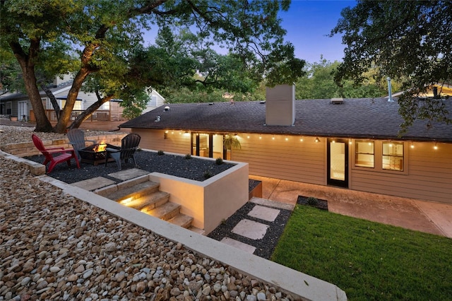 back house at dusk featuring an outdoor fire pit and a patio