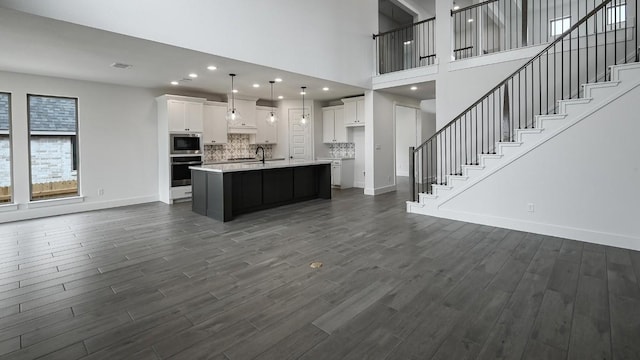 kitchen featuring open floor plan, dark wood-type flooring, stainless steel appliances, light countertops, and white cabinetry