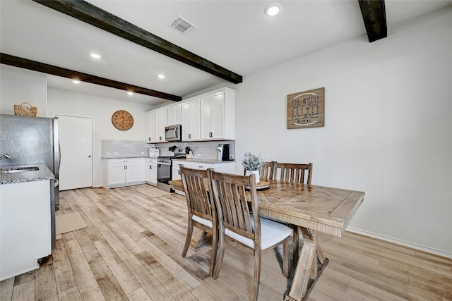 dining space featuring light hardwood / wood-style floors, beam ceiling, and sink