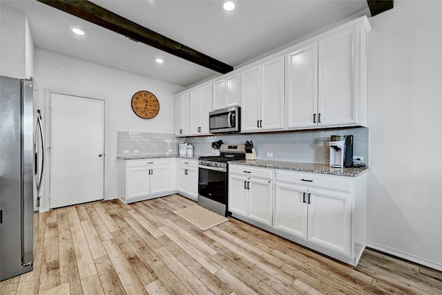 kitchen with beam ceiling, white cabinetry, stainless steel appliances, and light stone countertops