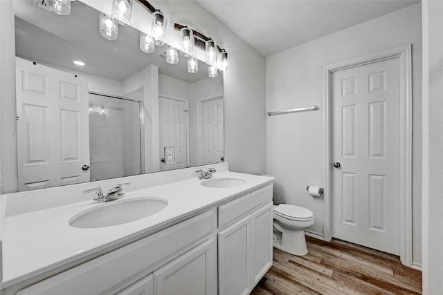 bathroom with toilet, hardwood / wood-style floors, vanity, and a shower