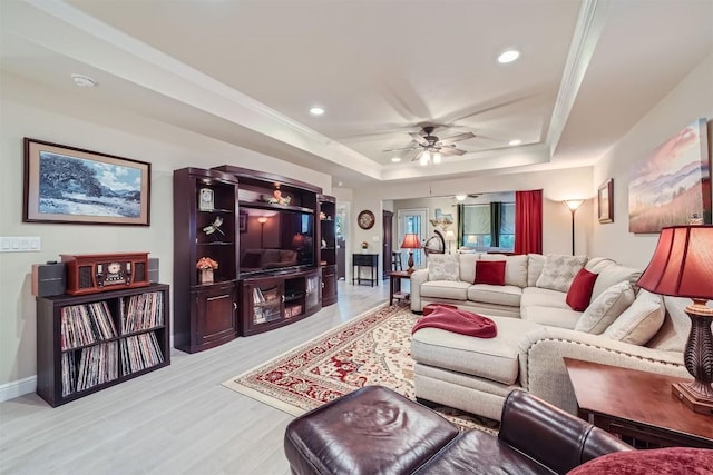 living room featuring ceiling fan, a raised ceiling, and light hardwood / wood-style flooring