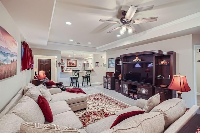 living room featuring light hardwood / wood-style floors, a raised ceiling, ceiling fan, and crown molding