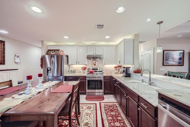 kitchen featuring white cabinetry, sink, stainless steel appliances, decorative light fixtures, and decorative backsplash