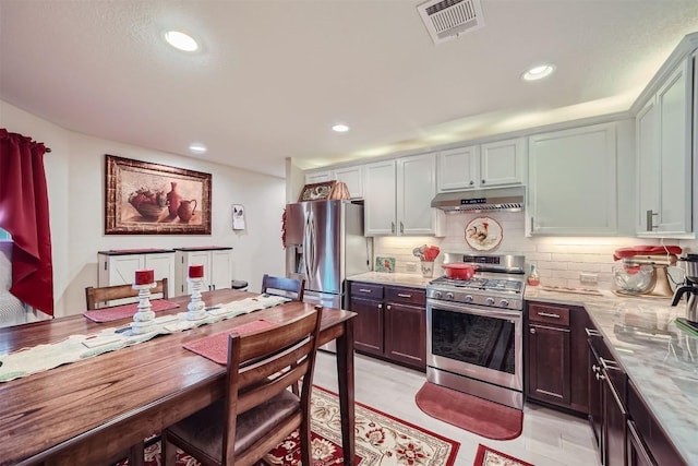 kitchen with sink, stainless steel appliances, light stone counters, light hardwood / wood-style flooring, and backsplash