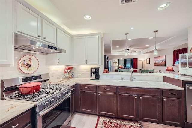 kitchen with stainless steel range with gas cooktop, sink, light stone countertops, light hardwood / wood-style floors, and white cabinetry