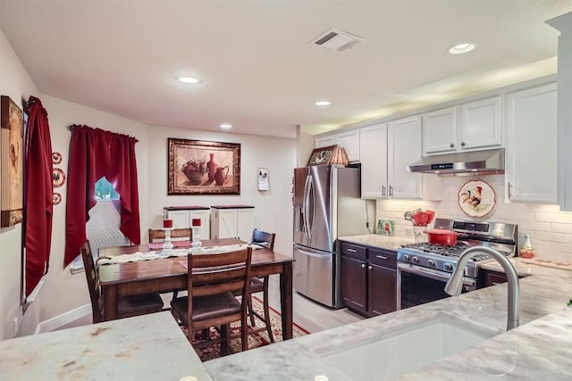 kitchen featuring sink, decorative backsplash, appliances with stainless steel finishes, light stone counters, and white cabinetry