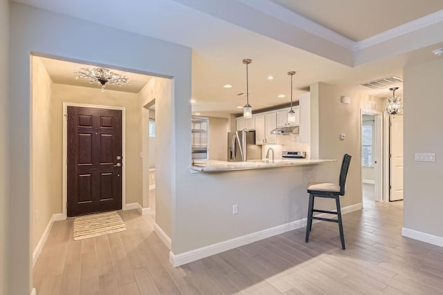 kitchen with pendant lighting, kitchen peninsula, stainless steel fridge, light wood-type flooring, and white cabinetry