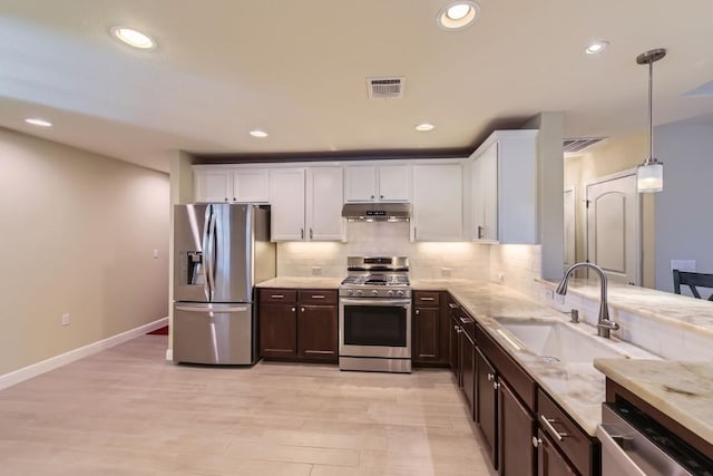 kitchen featuring appliances with stainless steel finishes, sink, decorative light fixtures, light hardwood / wood-style floors, and white cabinetry