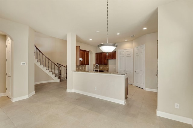 kitchen with decorative backsplash, light stone counters, hanging light fixtures, and light tile patterned floors