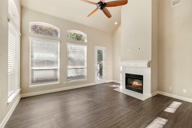 unfurnished living room with a tiled fireplace, high vaulted ceiling, dark hardwood / wood-style flooring, and ceiling fan