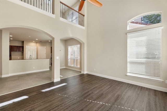 unfurnished living room featuring a high ceiling, wood-type flooring, and a healthy amount of sunlight