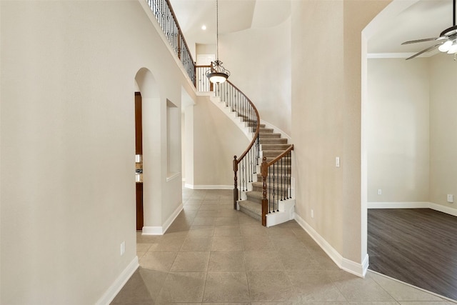 foyer with a towering ceiling, light wood-type flooring, and ceiling fan