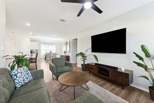 living room featuring light wood-type flooring and ceiling fan