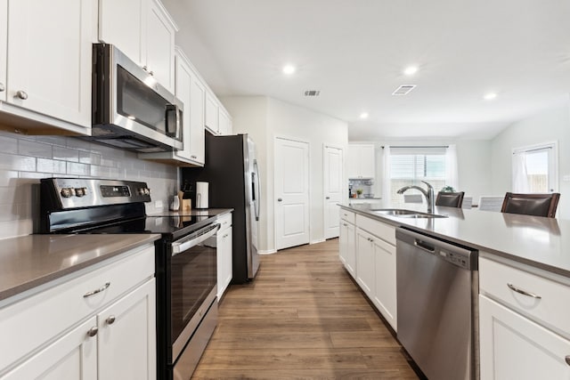 kitchen featuring white cabinets, tasteful backsplash, appliances with stainless steel finishes, dark wood-type flooring, and sink