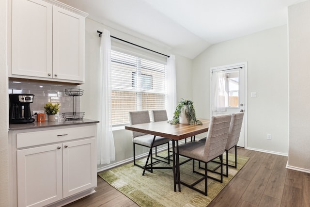 dining space featuring lofted ceiling, dark wood-type flooring, and plenty of natural light