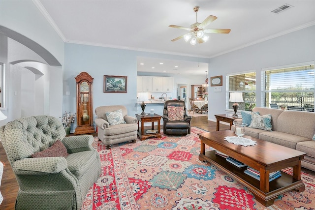 living room with crown molding, wood-type flooring, sink, and ceiling fan