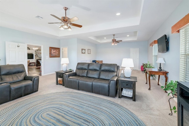 carpeted living room featuring a tray ceiling and ceiling fan