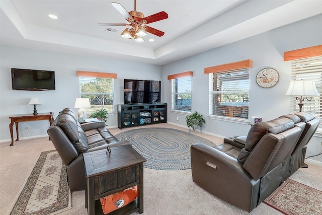 carpeted living room with ceiling fan and a tray ceiling