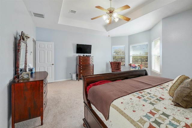 carpeted bedroom featuring a tray ceiling and ceiling fan