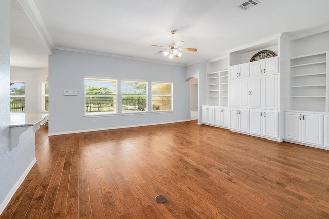 1900 County Road 245, Georgetown, TX 78633 - unfurnished living room featuring ceiling fan, wood finished floors, crown molding, arched walkways, and built in features