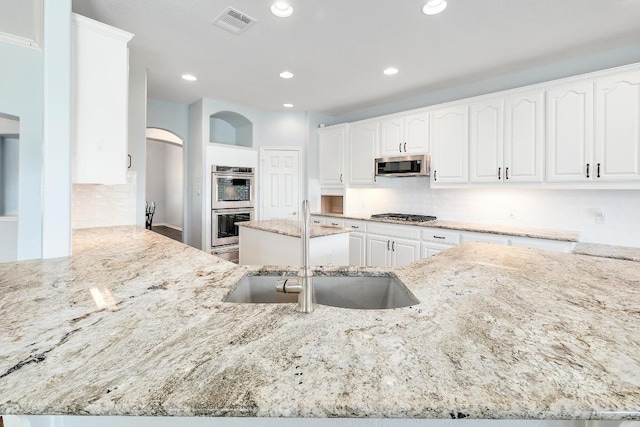1900 County Road 245, Georgetown, TX 78633 - kitchen with appliances with stainless steel finishes, arched walkways, light stone countertops, backsplash, and recessed lighting