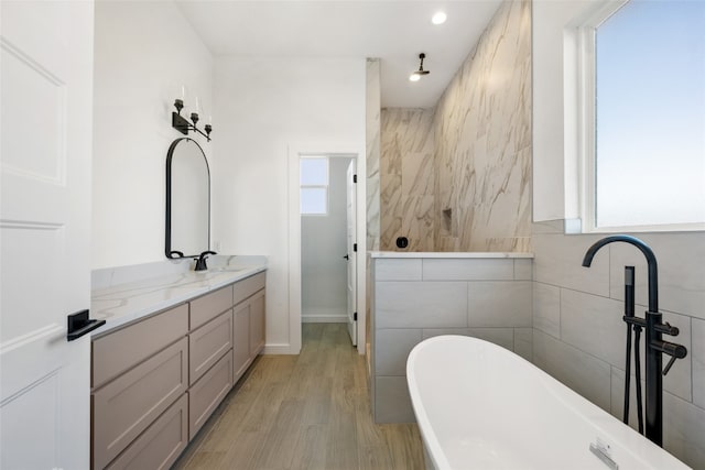 bathroom with vanity, a tub, hardwood / wood-style flooring, and tile walls