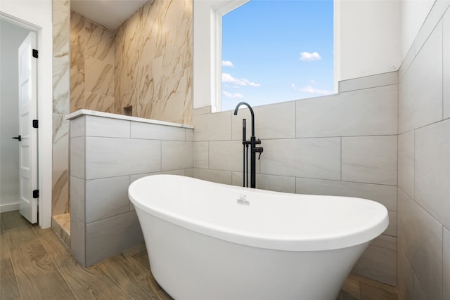 bathroom with tile walls, a washtub, and hardwood / wood-style floors