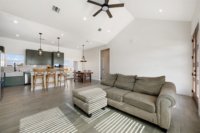 living room with sink, high vaulted ceiling, dark hardwood / wood-style flooring, and ceiling fan with notable chandelier