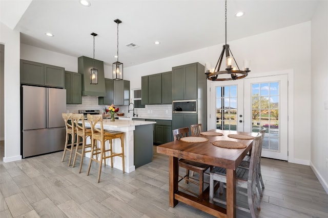 kitchen featuring light stone countertops, appliances with stainless steel finishes, a kitchen island, pendant lighting, and decorative backsplash