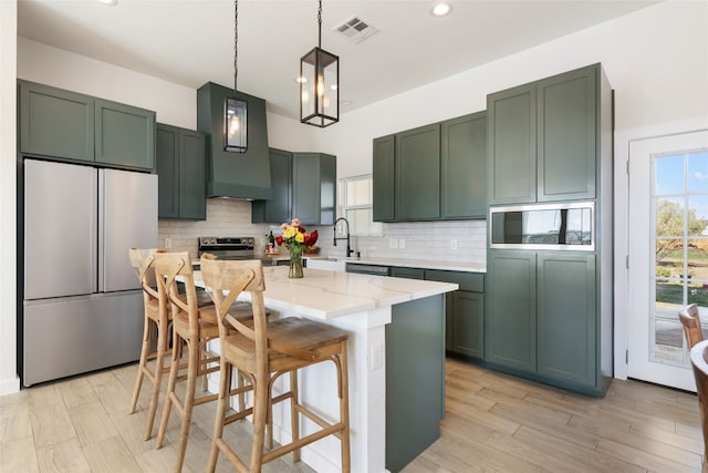 kitchen featuring a kitchen island, stainless steel appliances, pendant lighting, light stone counters, and decorative backsplash