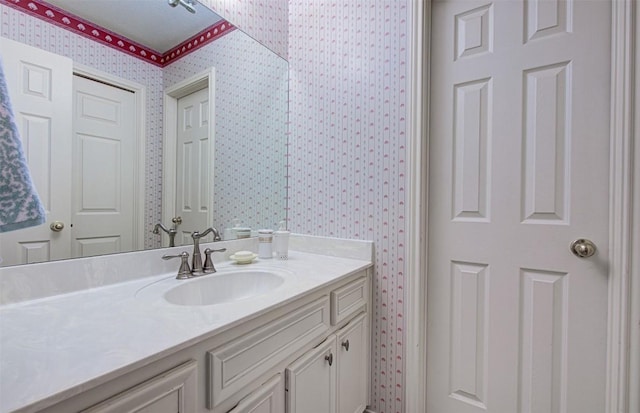 bathroom with vanity and wallpapered walls